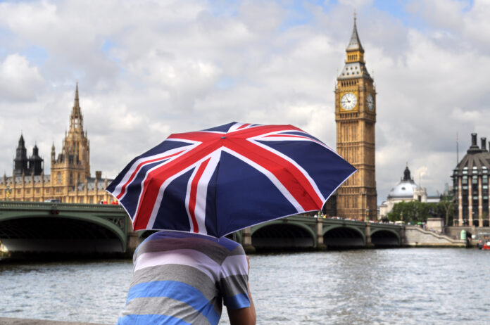 Big Ben and tourist with British flag umbrella in London